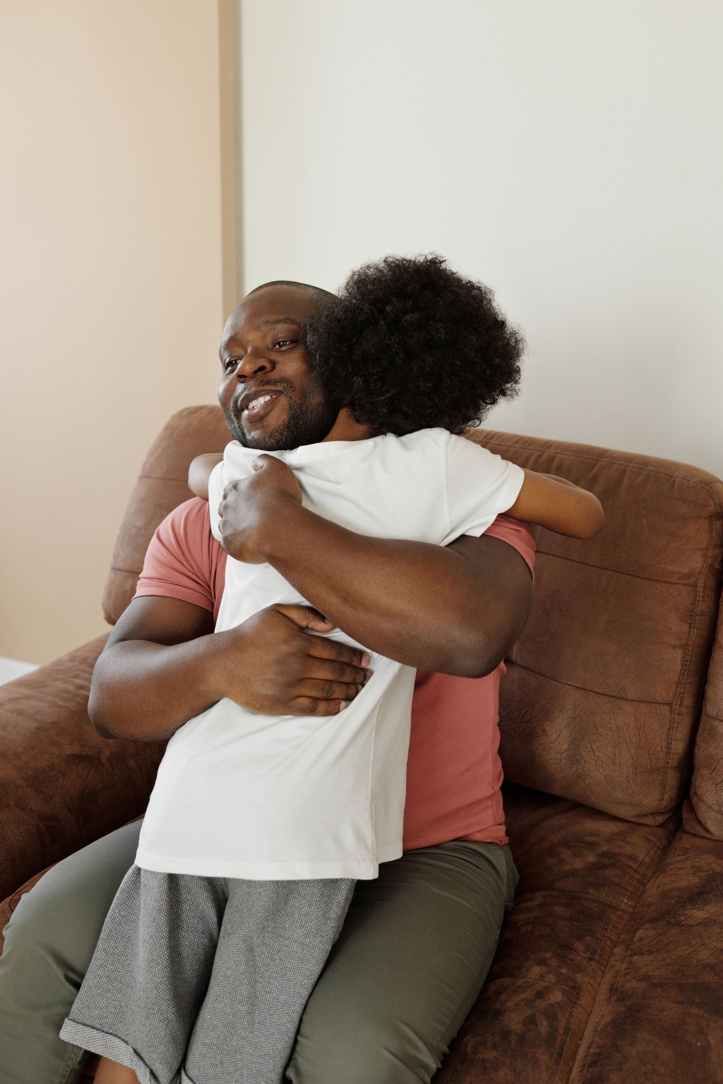 A veteran embracing their child on the couch at home