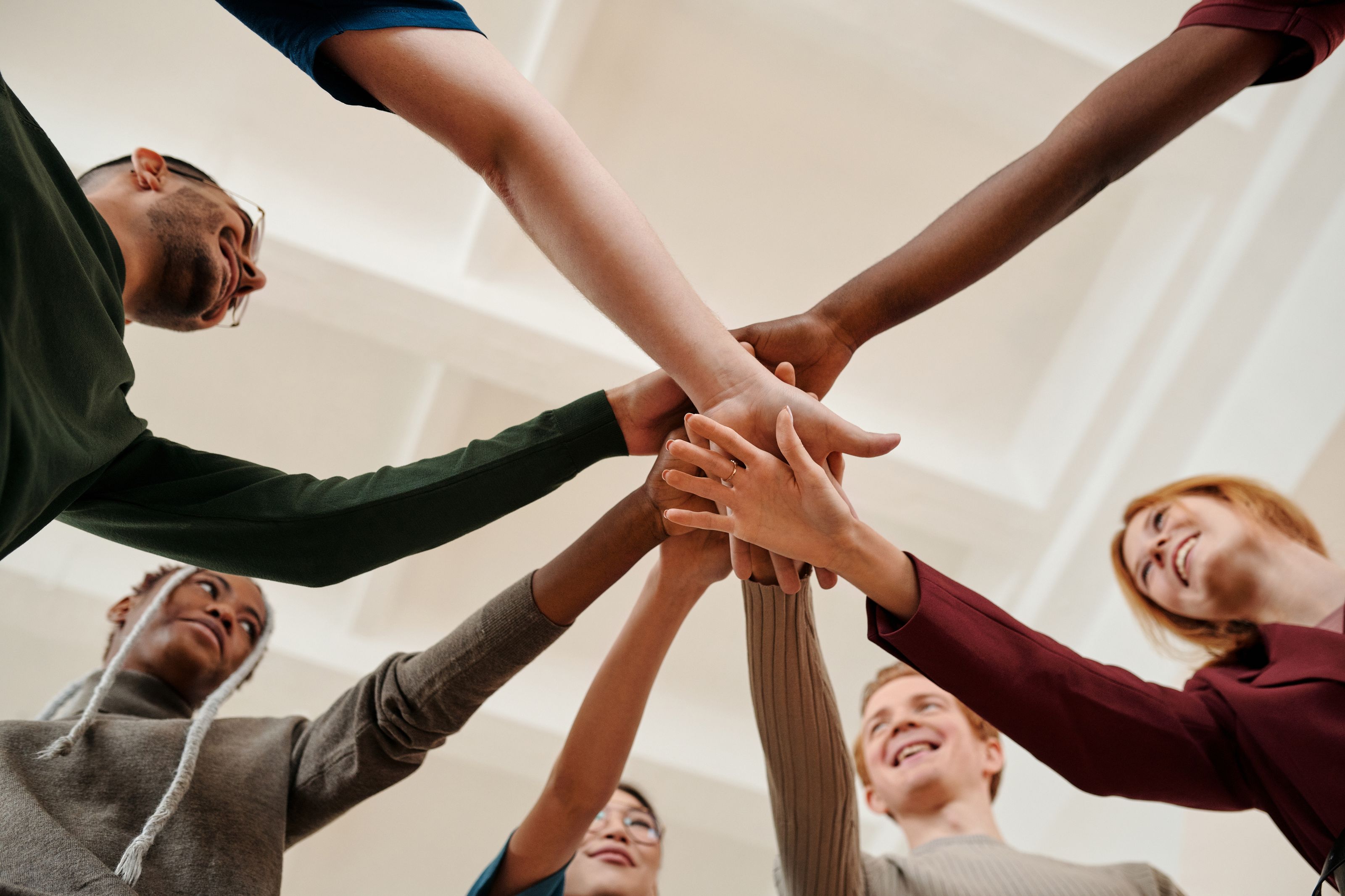 A diverse group joining hands together